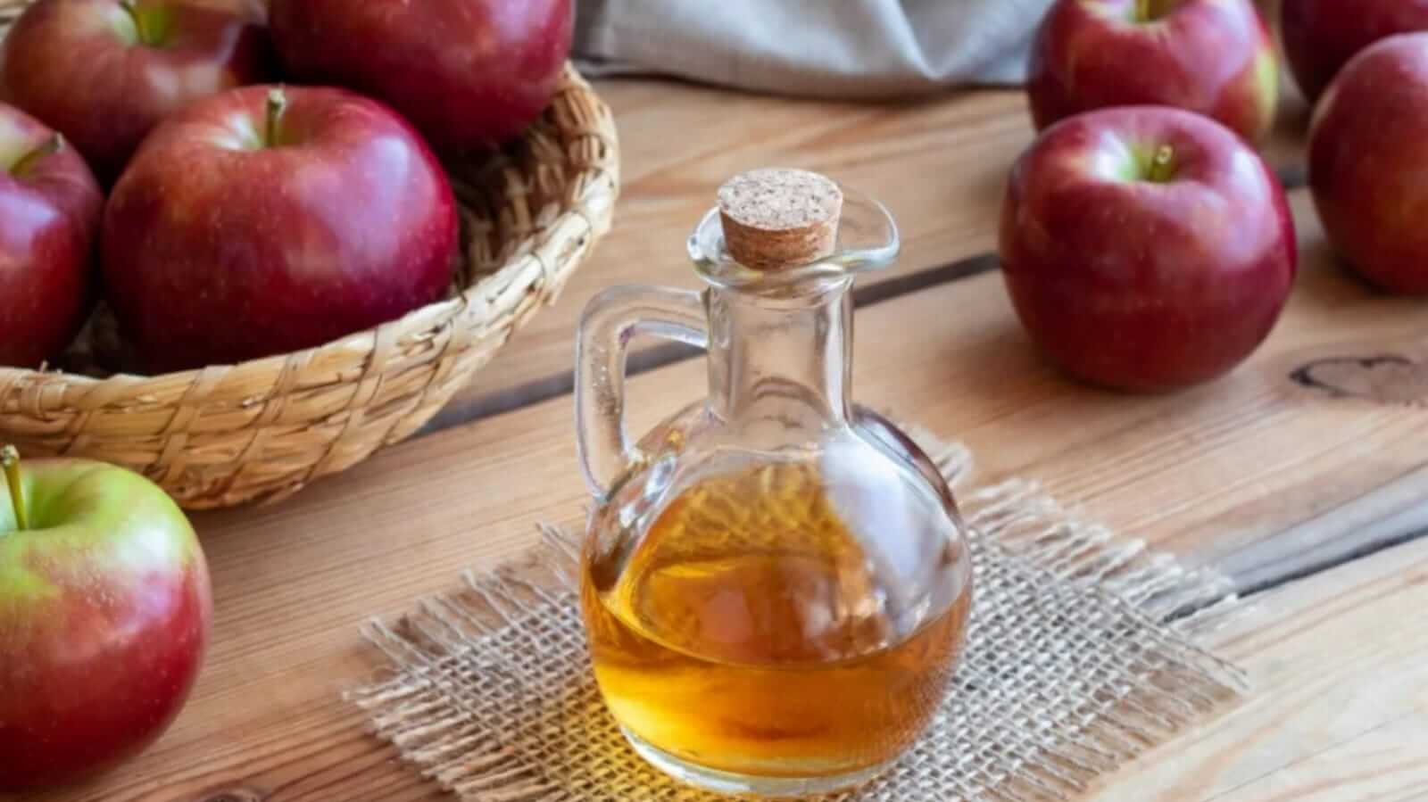 Frasco de vinagre com maçãs ao redor