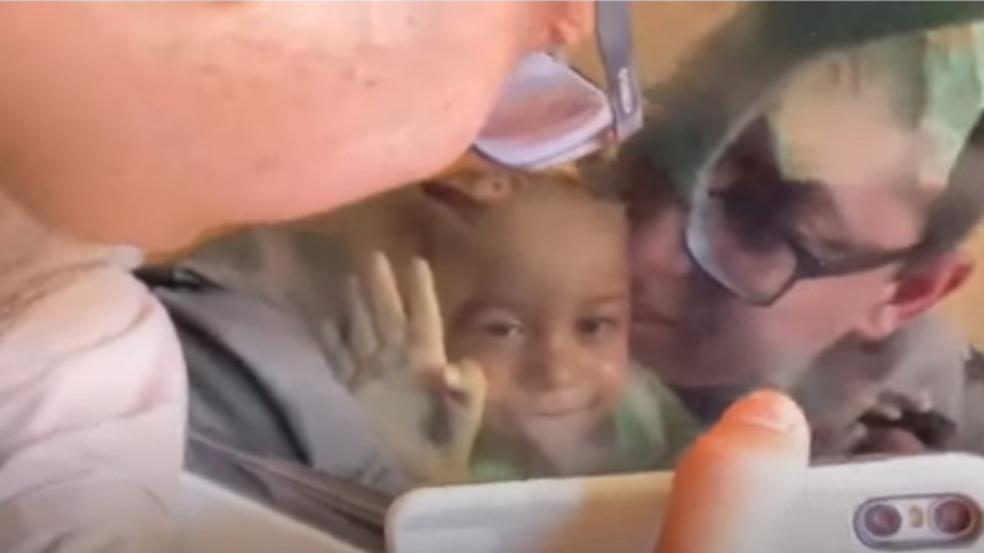 Homem mostrando celular para criança em carro