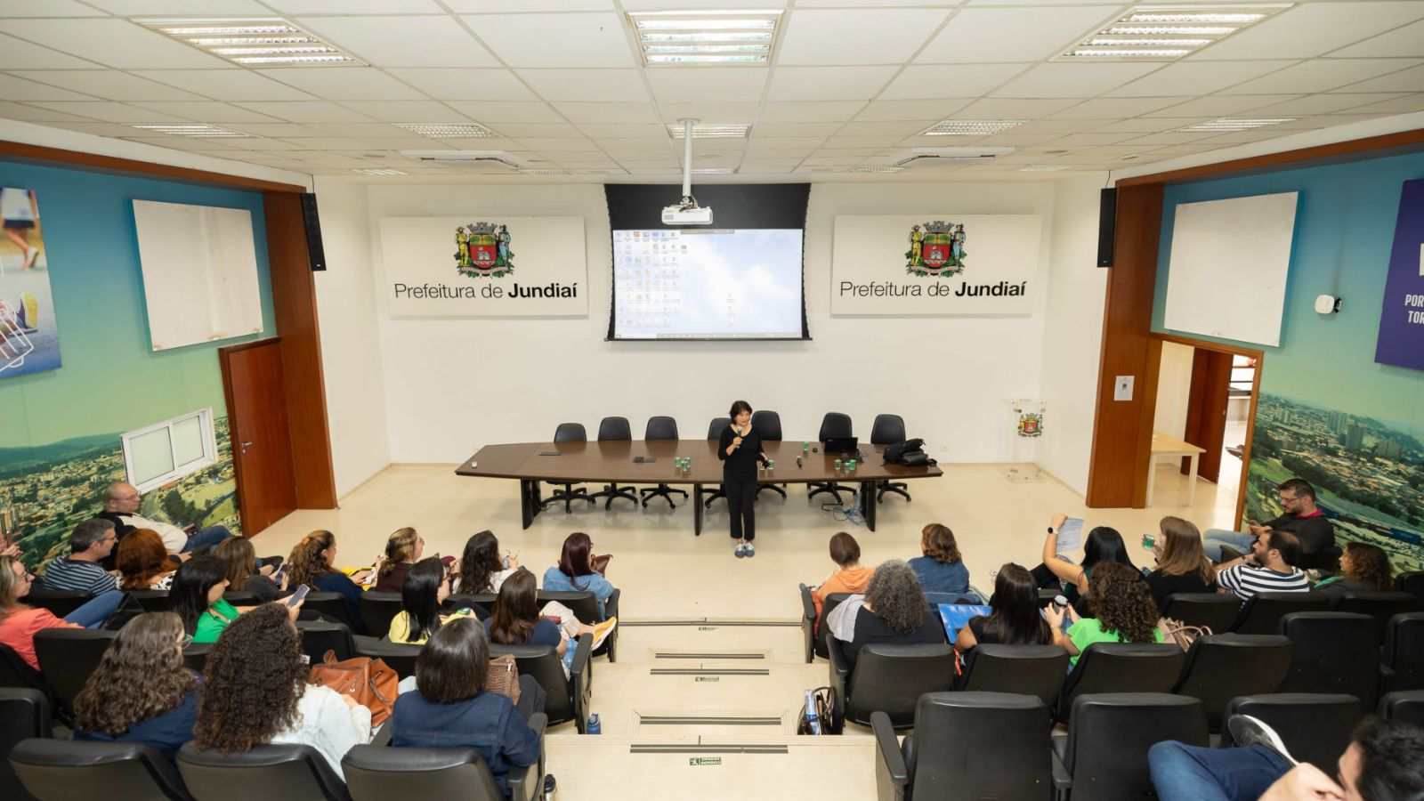 Palestrante fala a profissionais no auditório da Prefeitura de Jundiaí durante encontro sobre saúde do trabalhador.