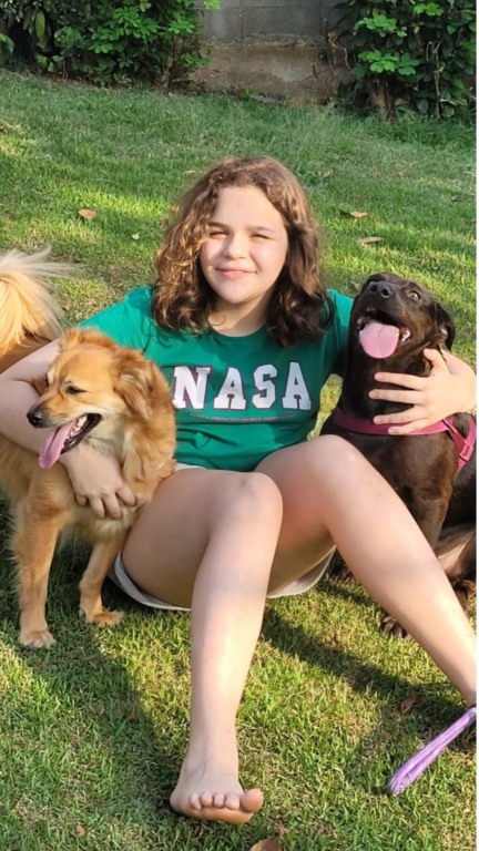 Menina abraçando dois cachorros