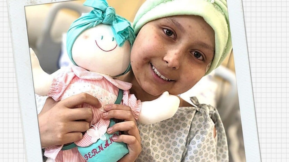 Menina abraçando boneca de pano