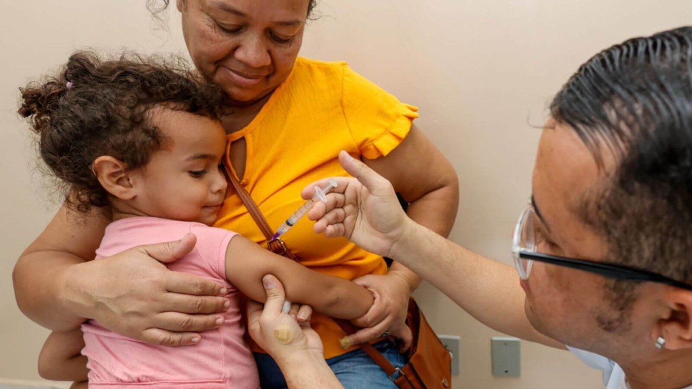 Profissional da saúde aplicando vacina em criança no colo da mãe em Jundiaí