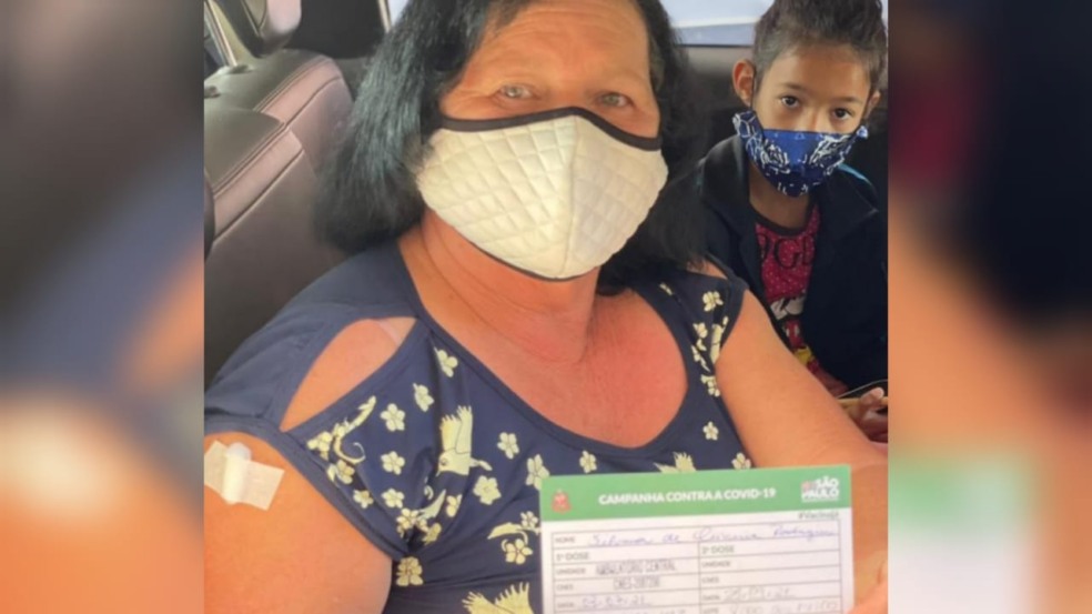 Mulher com cartão de vacinação contra Covid19