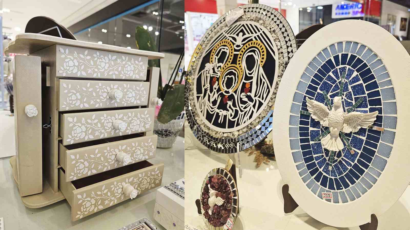Artesanatos expostos no Espaço Maxi Comunidade em Jundiaí, incluindo um porta-joias em madeira pintado com flores brancas e mosaicos decorativos com temas religiosos e artísticos, à venda em prol da Casa Neemias.