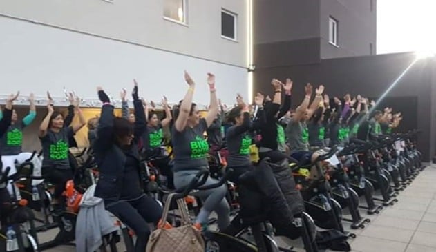 Grupo de homens e mulheres pedalando em equipamentos de academia