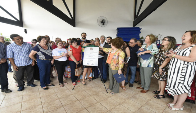 idosos e membros da prefeitura lado a lado durante cerramento da placa de inauguração da reforma do centro de conveniência do idoso