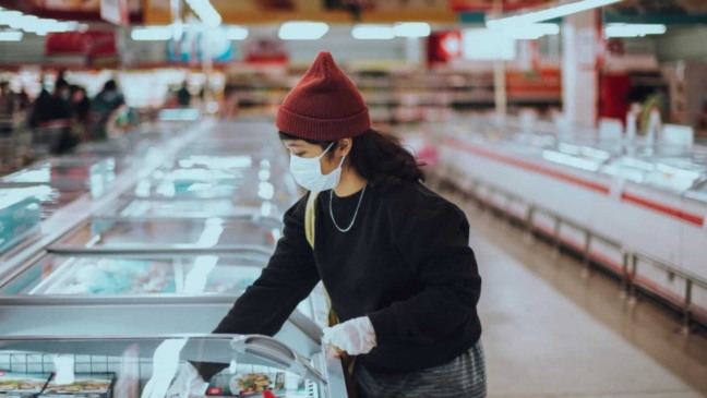 Mulher em supermercado com máscara