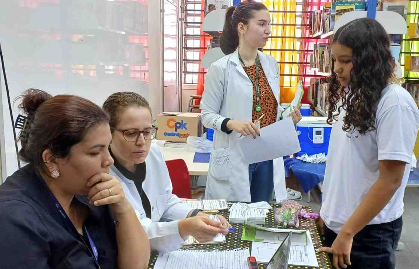 Profissionais da saúde orientam estudante durante ação de cobertura vacinal em escola de Jundiaí.