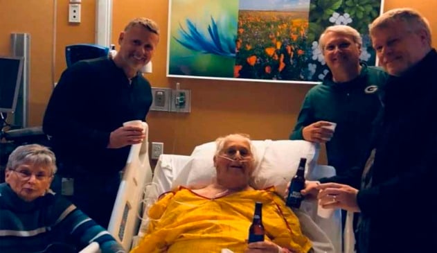 idoso em maca segurando uma cerveja ao lado dos seus três filhos e esposa