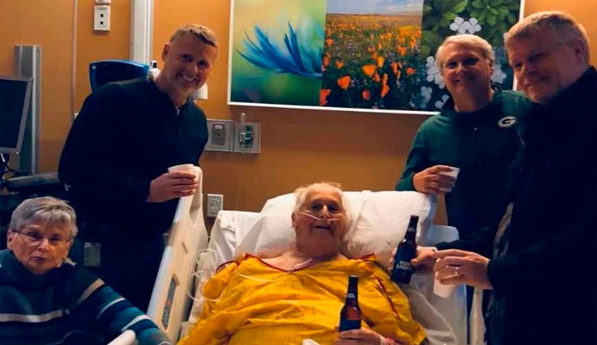 idoso em maca segurando uma cerveja ao lado dos seus três filhos e esposa