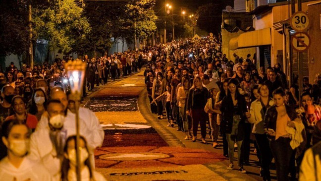 Procissão de Corpus Christi em Jundiaí com tapetes coloridos e grande número de fiéis, à noite.