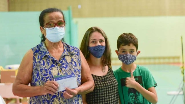 Duas mulheres e menino em vacinação contra Covid-19