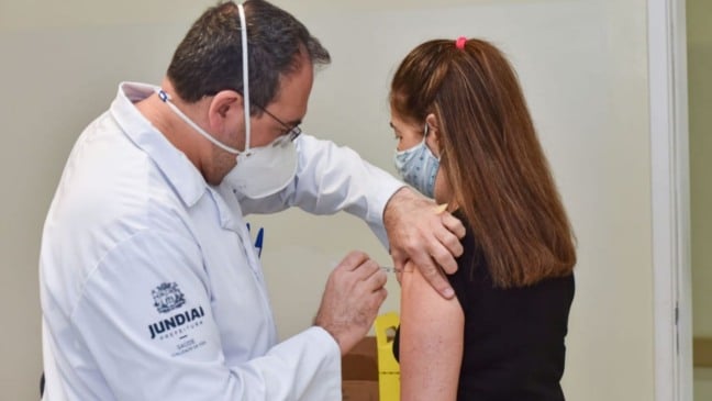 Homem vacinando jovem em Jundiai