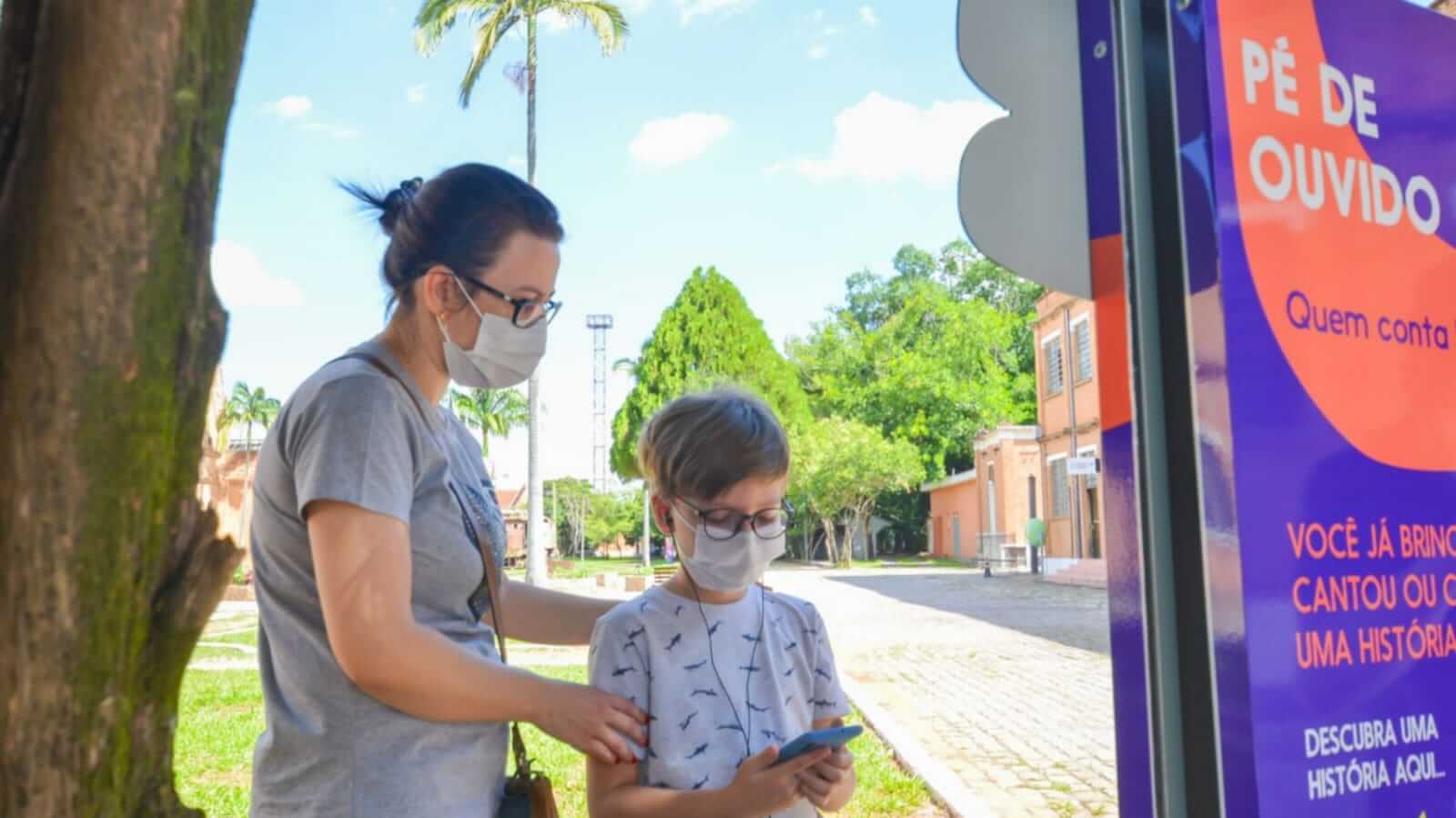 Mulher e menino em frente à totem do Pé de Ouvido