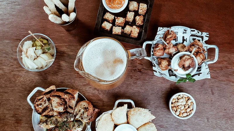 Mesa com jarra de cerveja e variadas porções vista sob o ângulo de cima