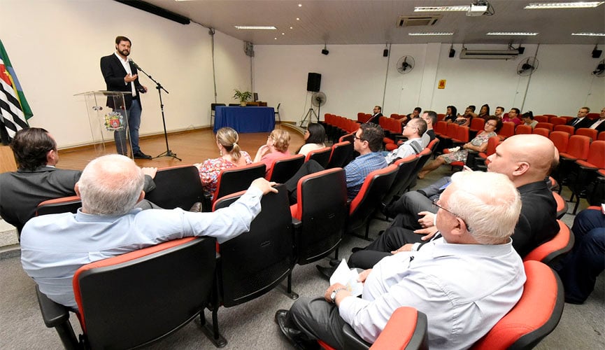 público em auditório acompanhando fala do prefeito de jundiaí no palco à frente