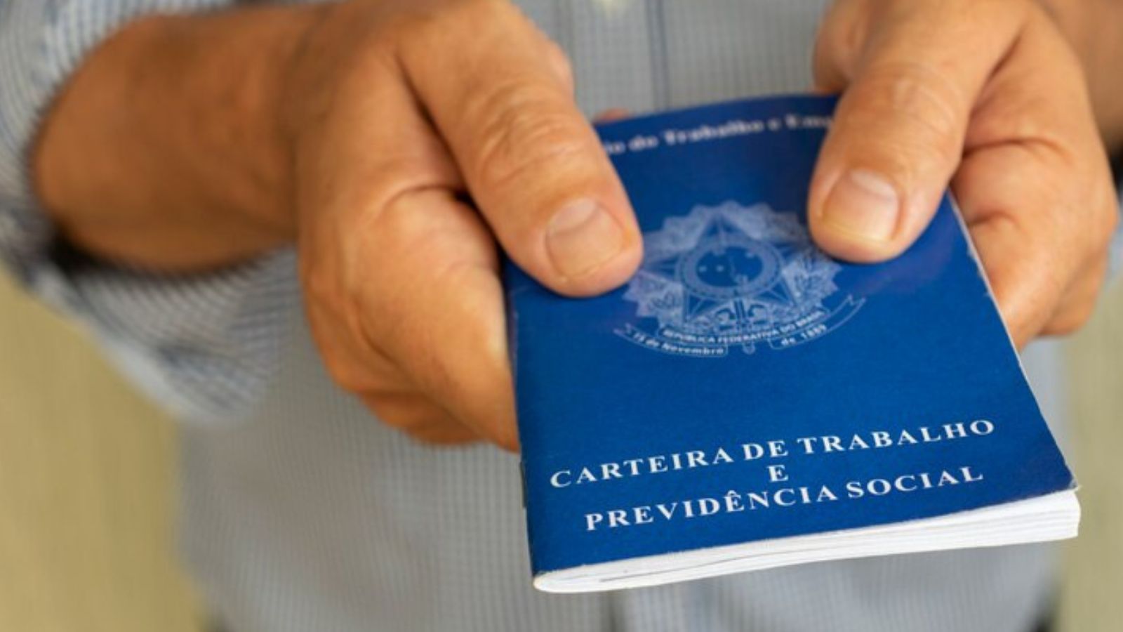 Vagas temporárias em Jundiaí exigem carteira de trabalho; foto de mãos masculinas segurando o documento.