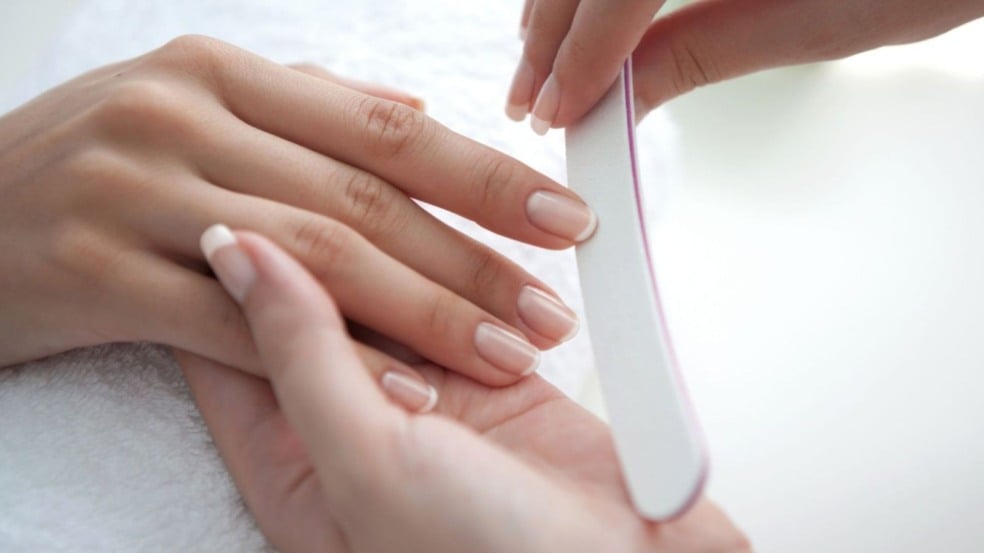 Mulher lixando a unha