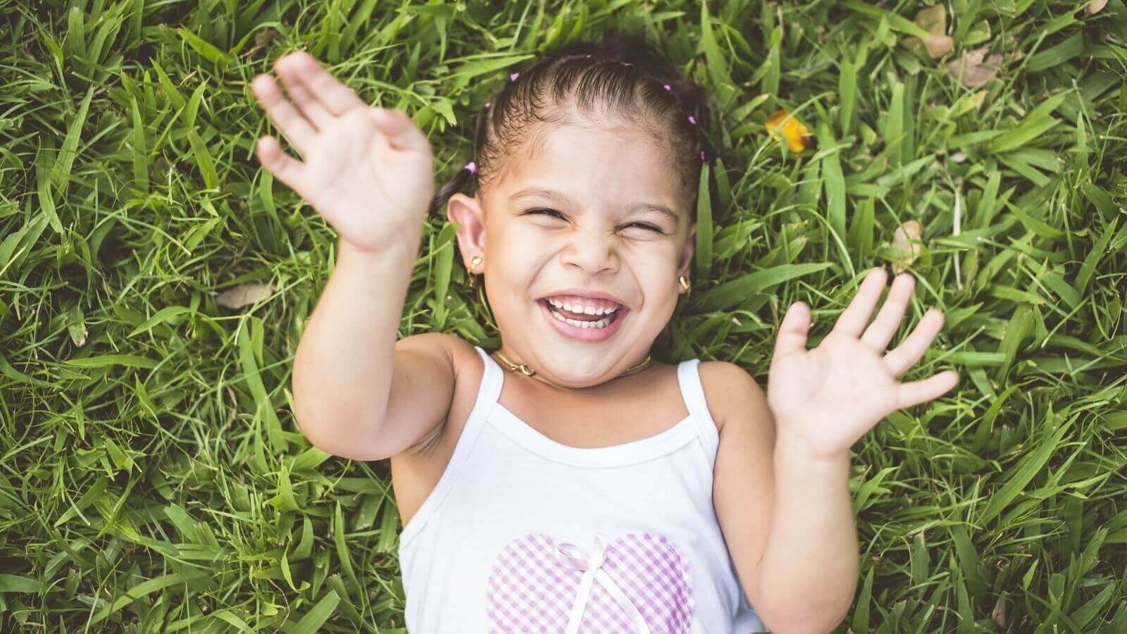 Criança sorrindo deitada na grama