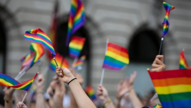 Pessoas levantando bandeira do Orgulho LGBTQIAP+