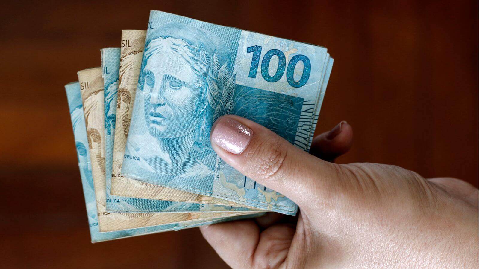 Pessoa segurando dinheiro em alusão ao dinheiro esquecido.