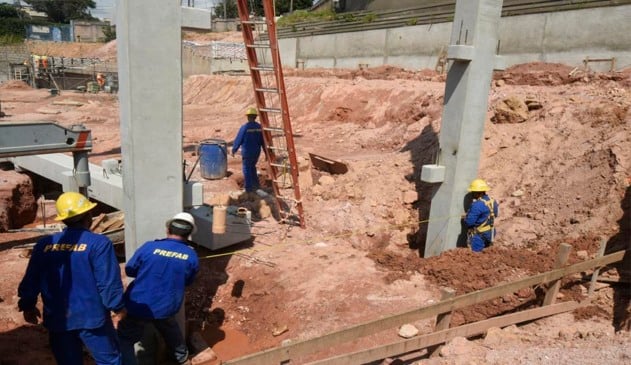 Pedreiros em obra onde estão sendo colocadas as primeiras vigas de cimento