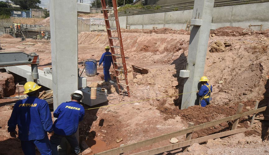 Pedreiros em obra onde estão sendo colocadas as primeiras vigas de cimento