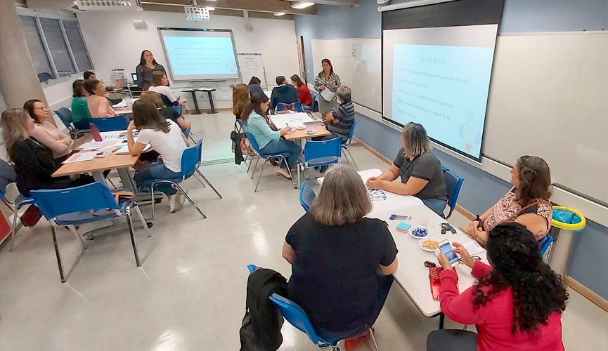 educadores sentados em mesas em sala durante fórum