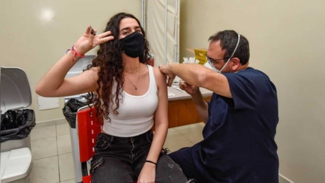 adolescente sentada sendo vacinada por profissional da saúde em Jundiaí