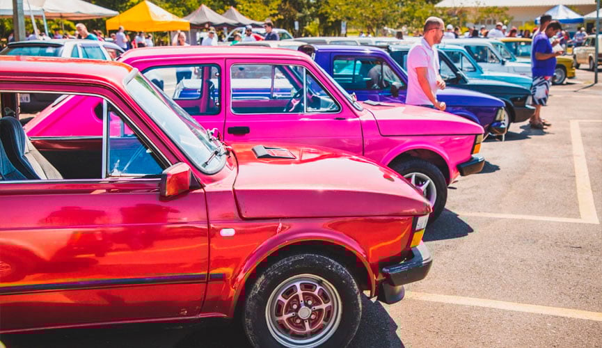 fiats 147 estacionados lado a lado, cada carro com vários cores