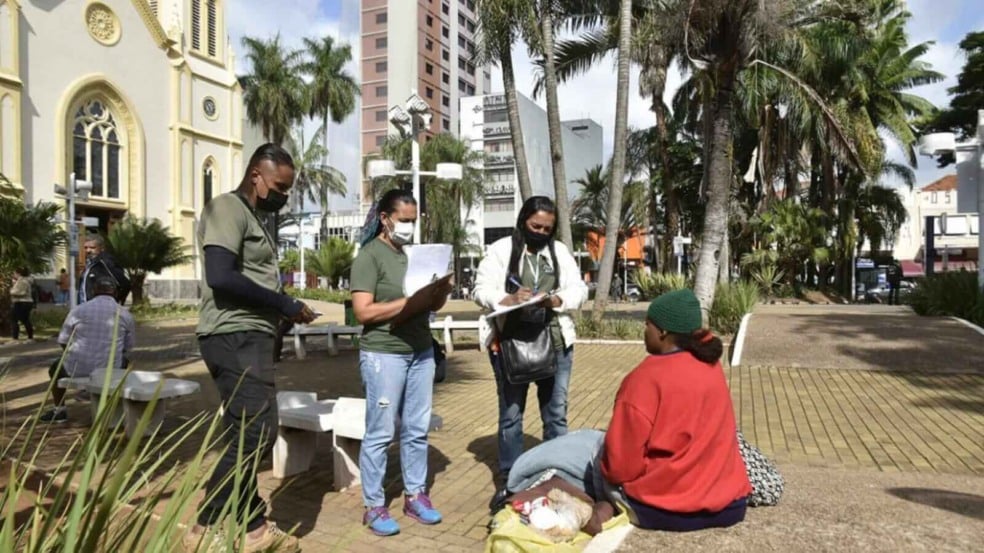 Três agentes da Operação Noites Frias abordando pessoa em situação de rua