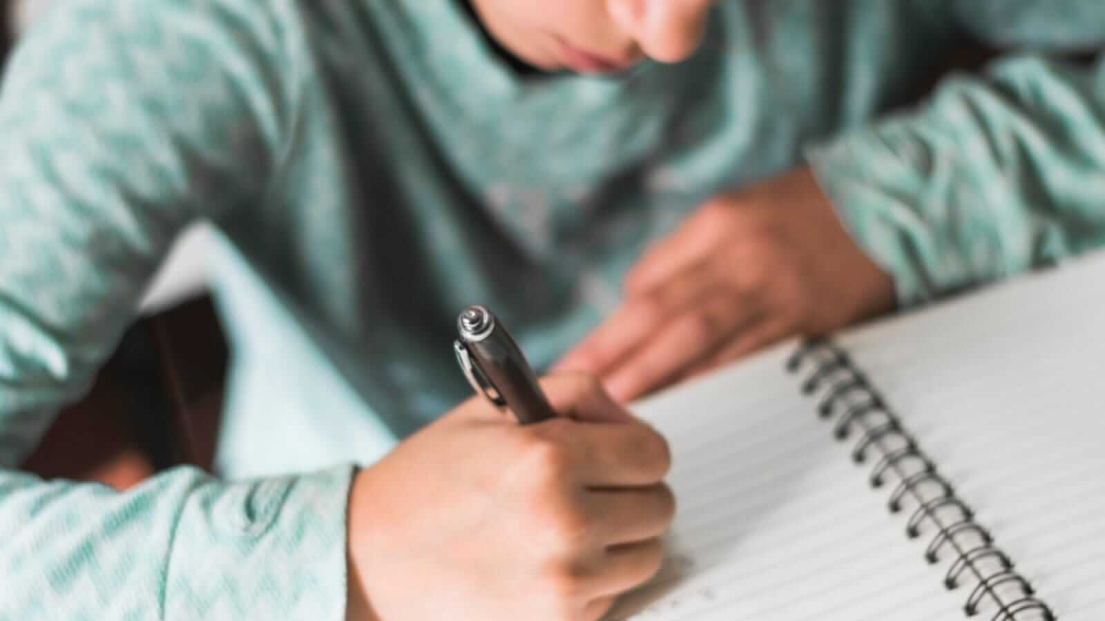 Menino escrevendo em caderno