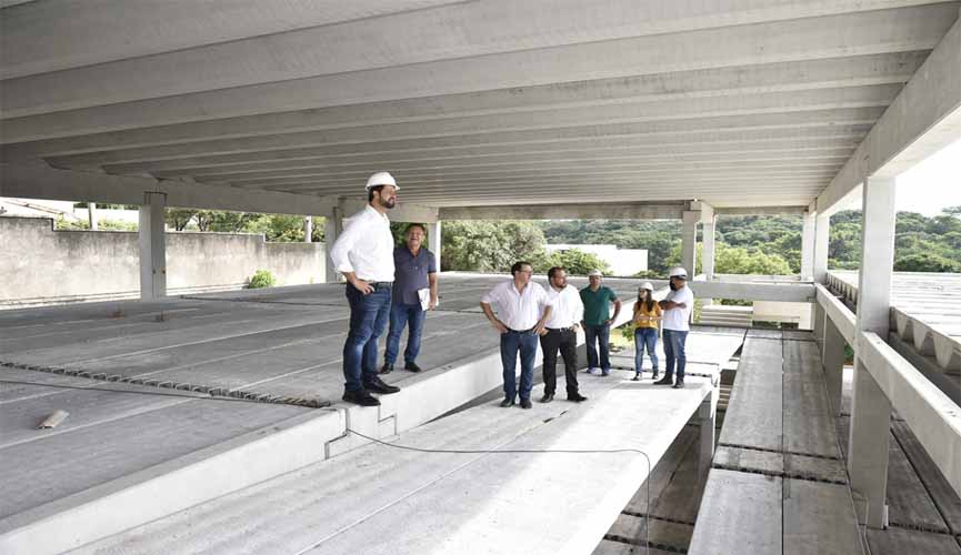 prefeito de jundiaí e funcionários vistoriam obra de nova escola municipal. prefeito e funcionários utilizam capacete de obras. eles estão dentro de um pavimento de blocos de concreto