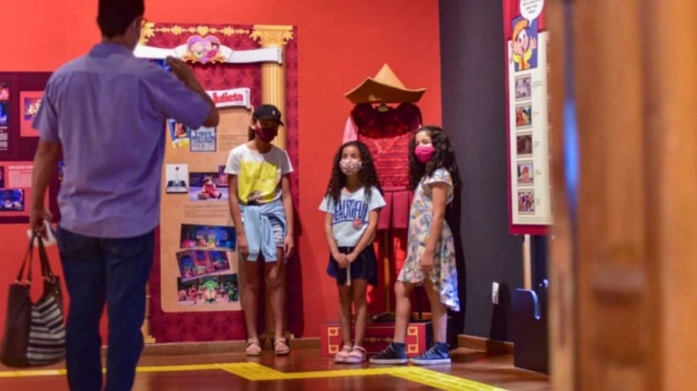 Homem tirando foto de três meninas em exposição de arte