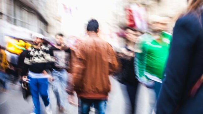 Pessoas agasalhadas em via pública para ilustrar a previsão do tempo para sábado.