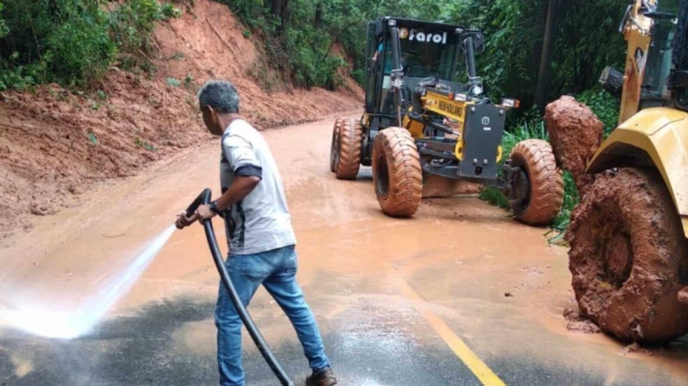 Homem lavando lama de estrada ao lado de trator em Campo Limpo Paulista