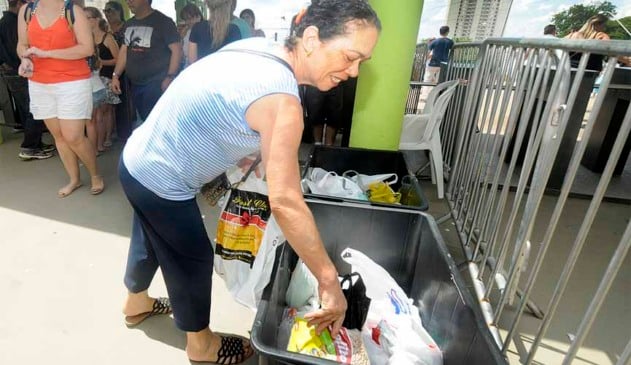 mulher depositando alimentos em caixa em frente ao parque da uva