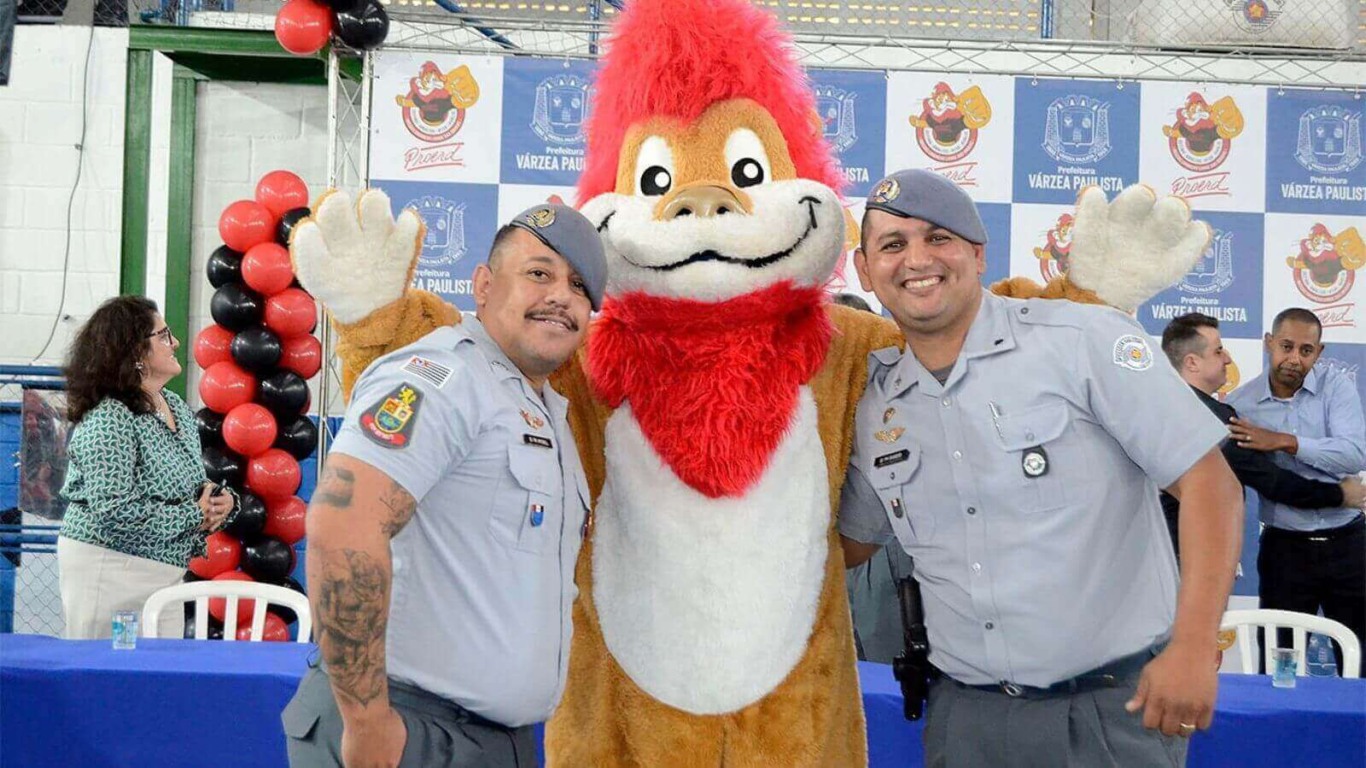 Policiais militares ao lado de mascote em tamanho real do PROERD