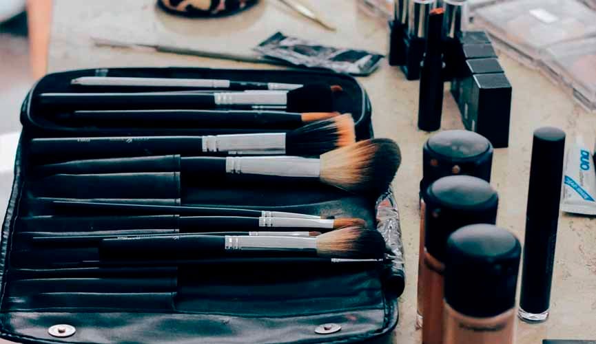 pinceis de maquiagens, bases de maquiagens e outros itens em uma mesa