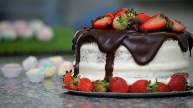 Bolo em mesa, com doces ao redor