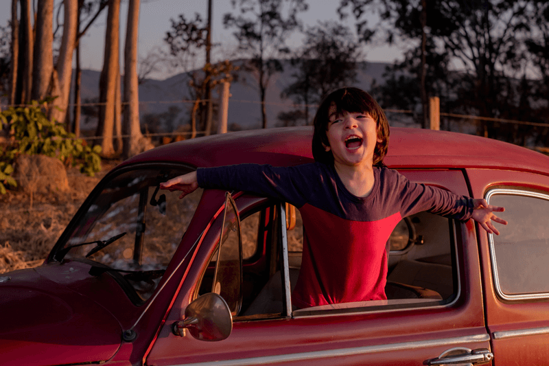 Emanuel com braços abertos pela janela do fusca