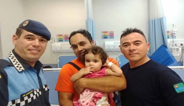 guarda municipal ao lado de familiares de bebê que foi salva pelo guarda após desmaio