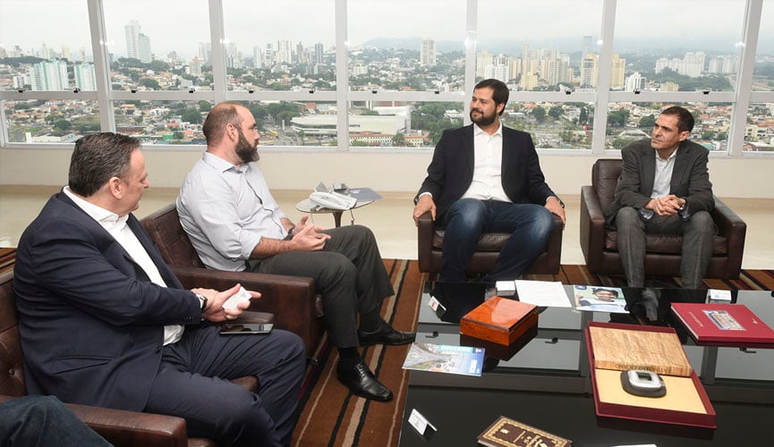 Reunião no gabinete do prefeito de Jundiaí, comdois empresários sentados à esquerda e prefeito e gestor sentados à direita, com cidade de jundiaí ao fundo pela janela