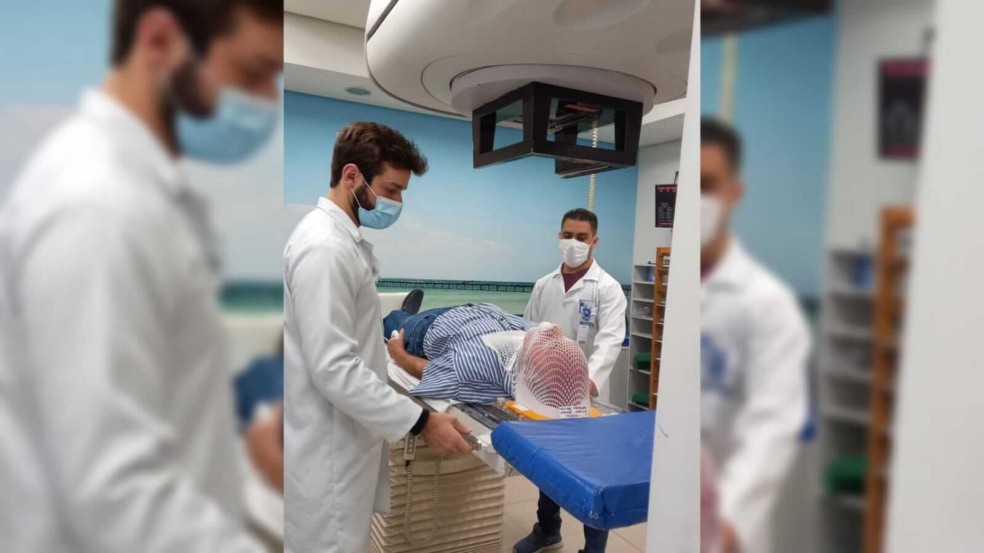 Três pessoas em uma sala de radioterapia