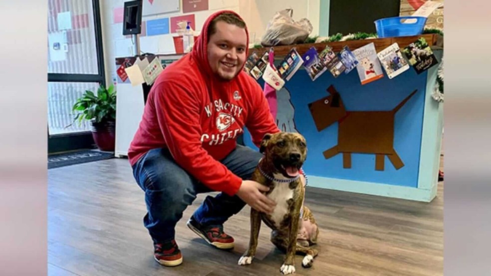 Homem posando ao lado de cachorro