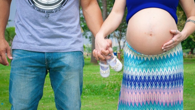 Gestante e homem dando as mãos