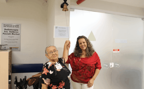 Dona Irene e a filha, Valéria, tocando sino símbolo do fim do tratamento.