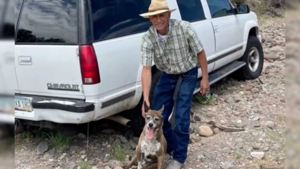 Homem e cachorro na frente de um carro branco