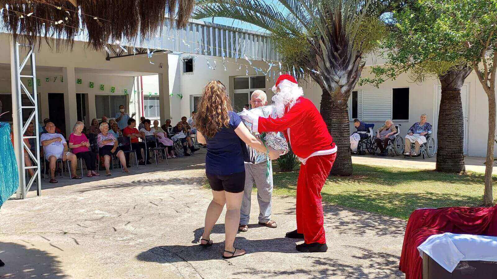 Papai Noel entregando presente para idoso