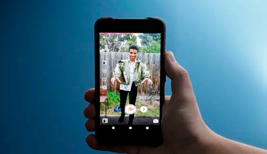 mão segura celular mostrando nova funcionalidade dos Stories do Intagram. o fundo da foto é azul